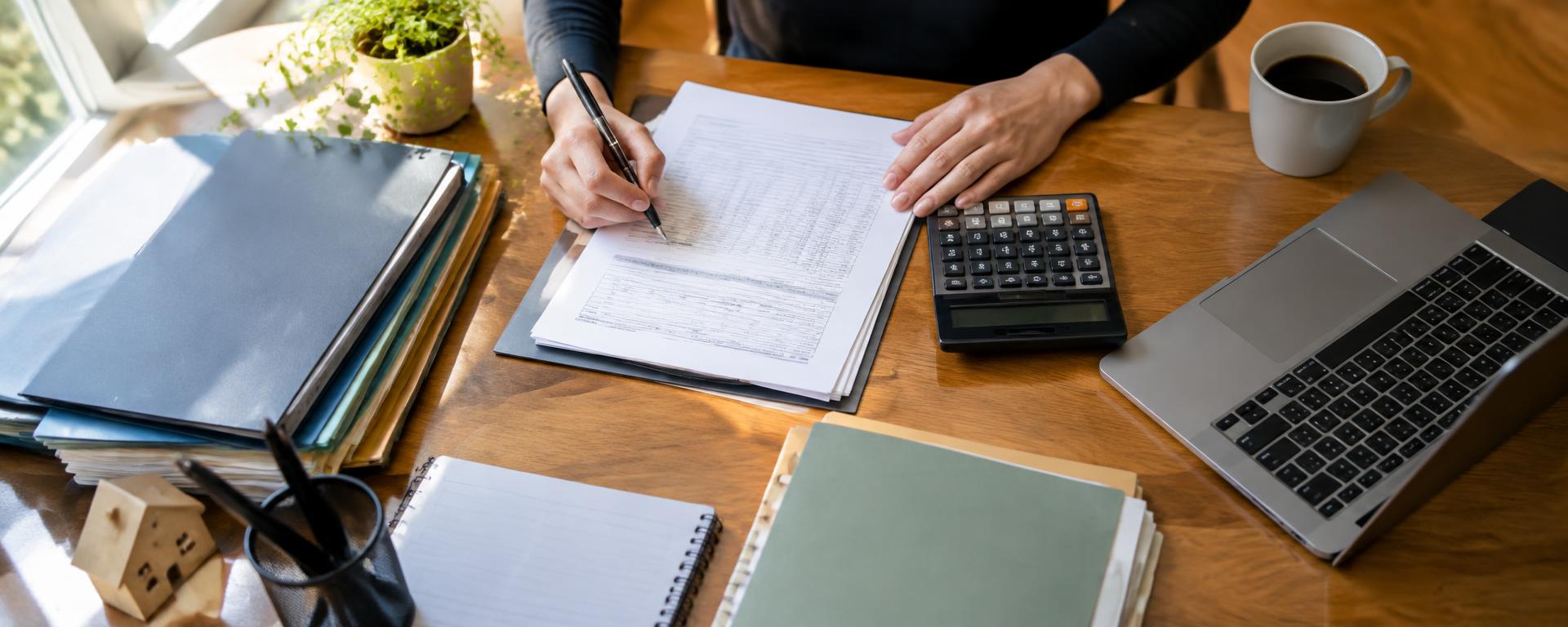 Bürotisch mit Unterlagen und arbeitenden Händen